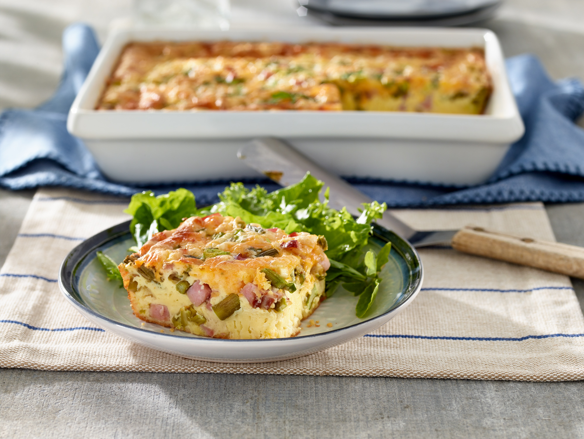 Slice of savory ham and cheese quiche with greens