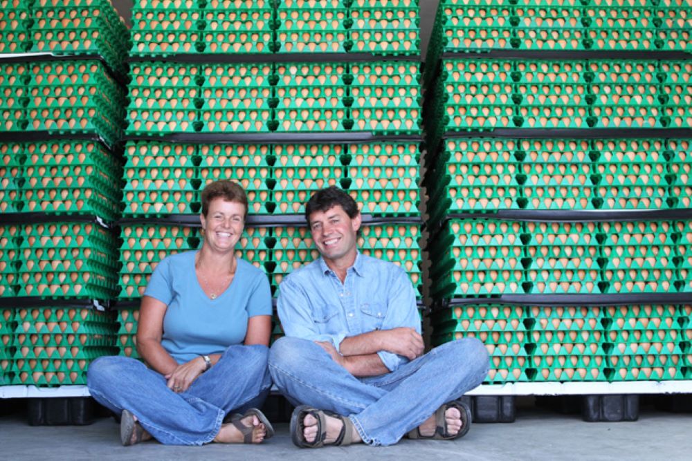 Two entrepreneurs smiling in front of egg crates.