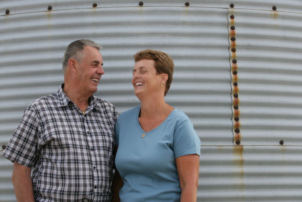 Happy older couple standing in front of silo
